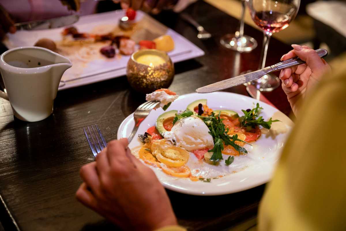 Mercato alimentare di Pienza con banchi di pecorino, salumi, ortaggi freschi, clienti e atmosfera vivace nel borgo